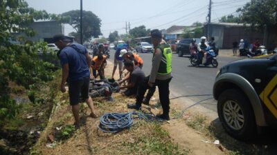 Petugas kepolisian dibantu relawan dan warga berusaha mengevakuasi motor korban dari dasar sungai, Minggu (1/10/2023). (Hasan/KabarTerdepan.com) 