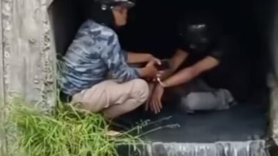Salah seorang terduga pencuri diborgol polisi di saluran air di Kedung Cowek Surabaya untuk menghindari amukan massa, Senin (18/3/2024). (Catur/kabarterdepan.com)