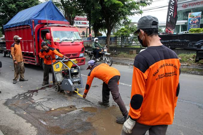 Sejumlah pekerja dari Dinas Bina Marga saat menambal jalan yang rusak akibat banjir. (Ahmad/kabarterdepan.com) 