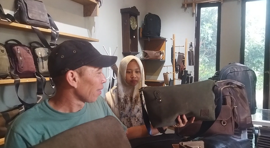 Sadzily menunjukkan tas kulit wanita yang banyak diminati pembeli, Sabtu (13/7/2024). (Redaksi/kabarterdepan.com) 