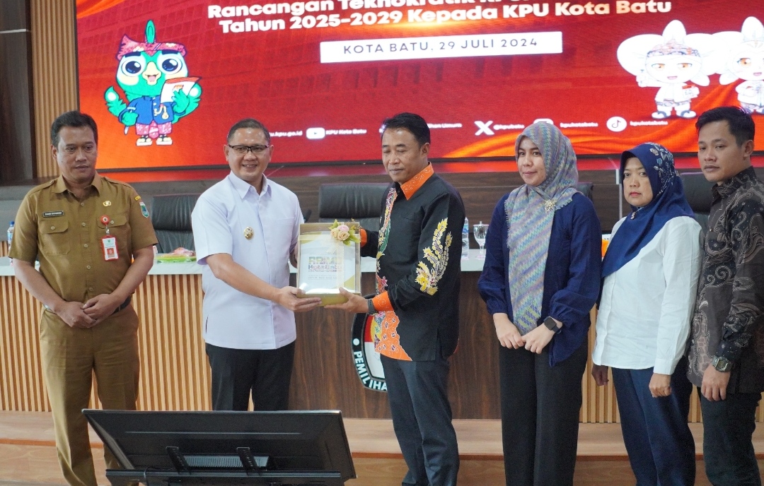 Pj. Wali Kota Batu Aries Agung Paewai, saat menyerahkan dokumen rancangan teknokratik kepada Ketua KPU Heru Joko Purwanto. (Yan)