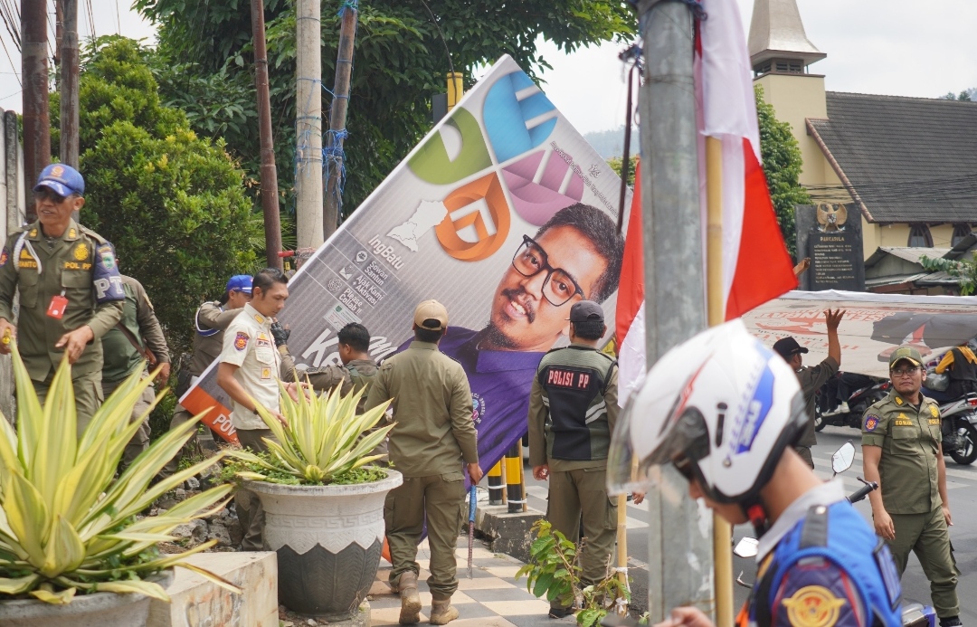 Satpol PP Kota Batu bersama petugas gabungan TNI-Polri, saat tengah menertibkan APK Parpol. (Yan)