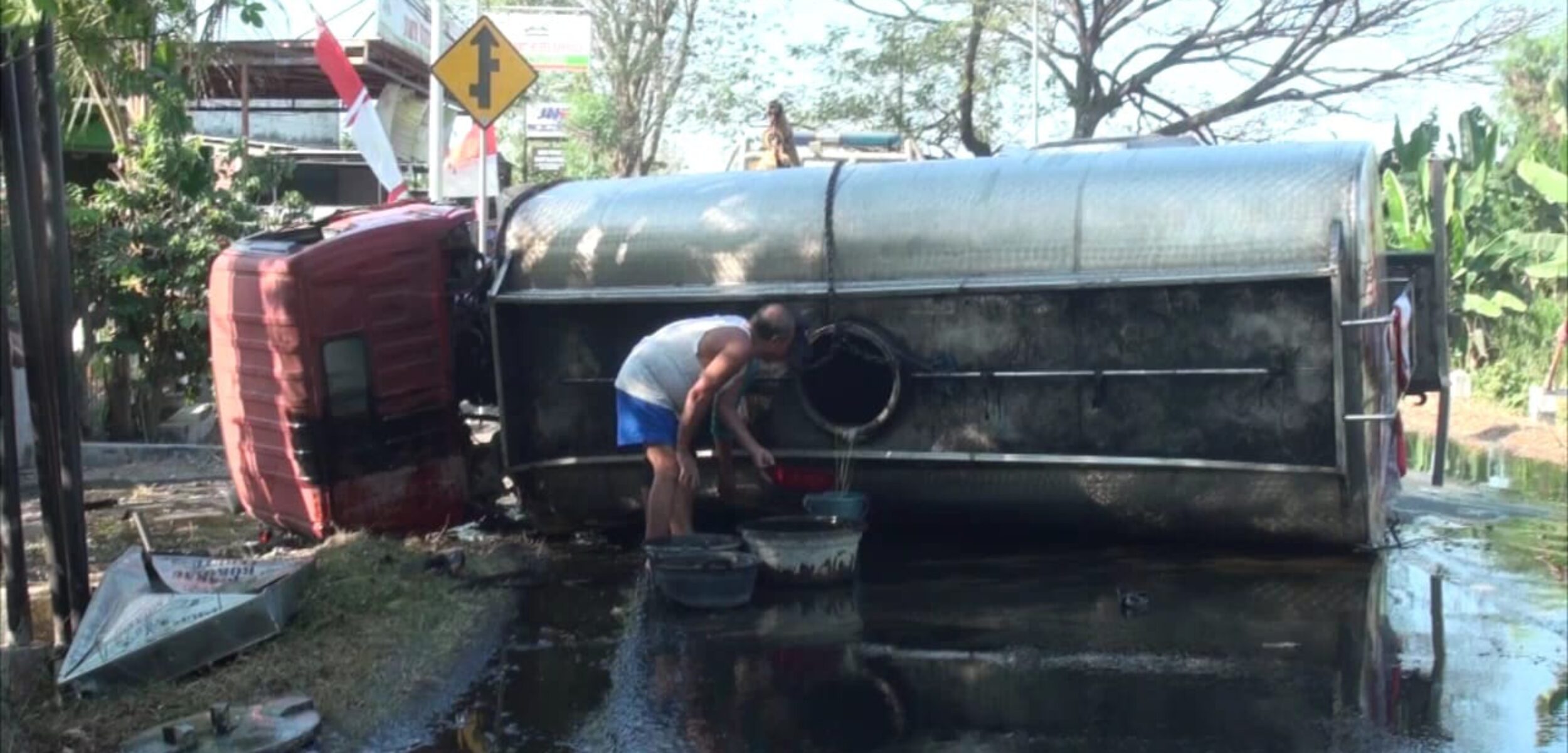 Warga berebut minyak goreng yang tumpah di jalan usai truk tangki bermuatan minyak 7 tinggal terlihat kecelakaan dengan truk tronton hingga terbalik di Jalan Raya Jetis, Kecamatan Jetis, Kabupaten Mojokerto, Senin (12/8/2024) sore