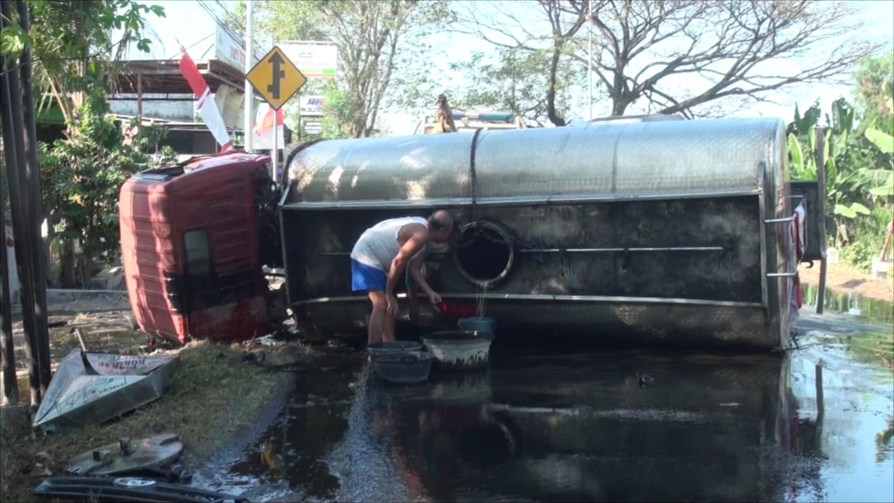 Warga berebut minyak goreng yang tumpah di jalan usai truk tangki bermuatan minyak 7 tinggal terlihat kecelakaan dengan truk tronton hingga terbalik di Jalan Raya Jetis, Kecamatan Jetis, Kabupaten Mojokerto, Senin (12/8/2024) sore