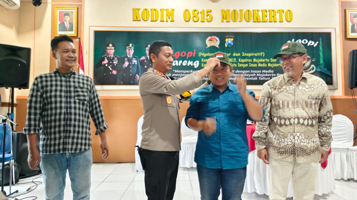 Kapolres Mojokerto Kota, AKBP Daniel S Marunduri memakaikan topi ke Ketua PWI Mojokerto Sholahuddin sebagai bentuk sinergitas TNI - POLRI dan awak media