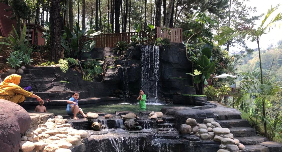 Pengunjung menikmati kolam renang dan air terjun buatan di kawasan hutan pinus milik Perhutani, Desa Trawas, Kecamatan Trawas, Kabupaten Mojokerto (Andy / Kabarterdepan.com)
