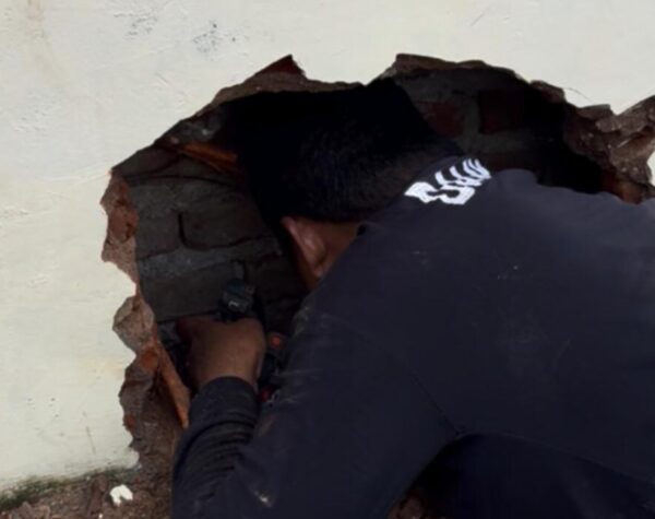 Petugas Damkar Kota Mojokerto berupaya mengevakuasi handphone yang terjatuh di antara dinding (Andy /Kabarterdepan.com) 