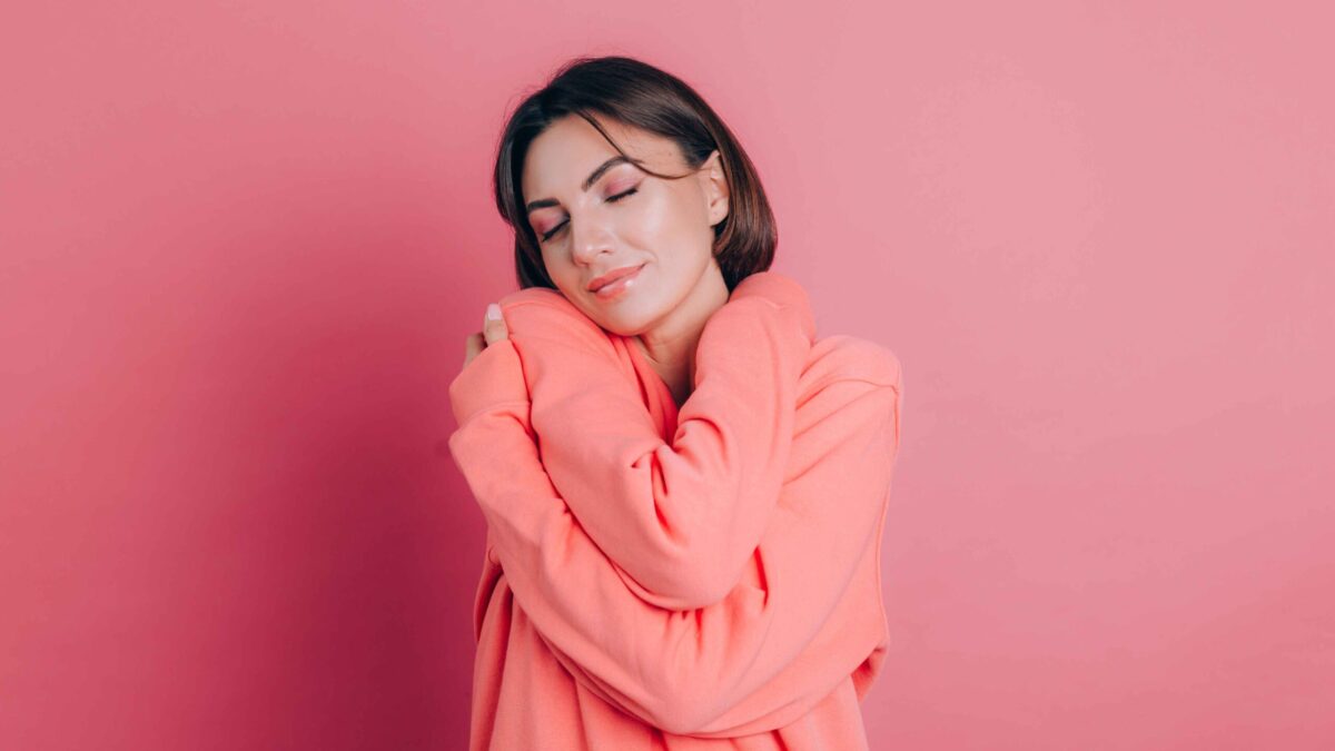 smiling young woman 20s casual clothes isolated pink background studio portrait love concept keeping eyes closed holding hands crossed hugging herself 11zon scaled