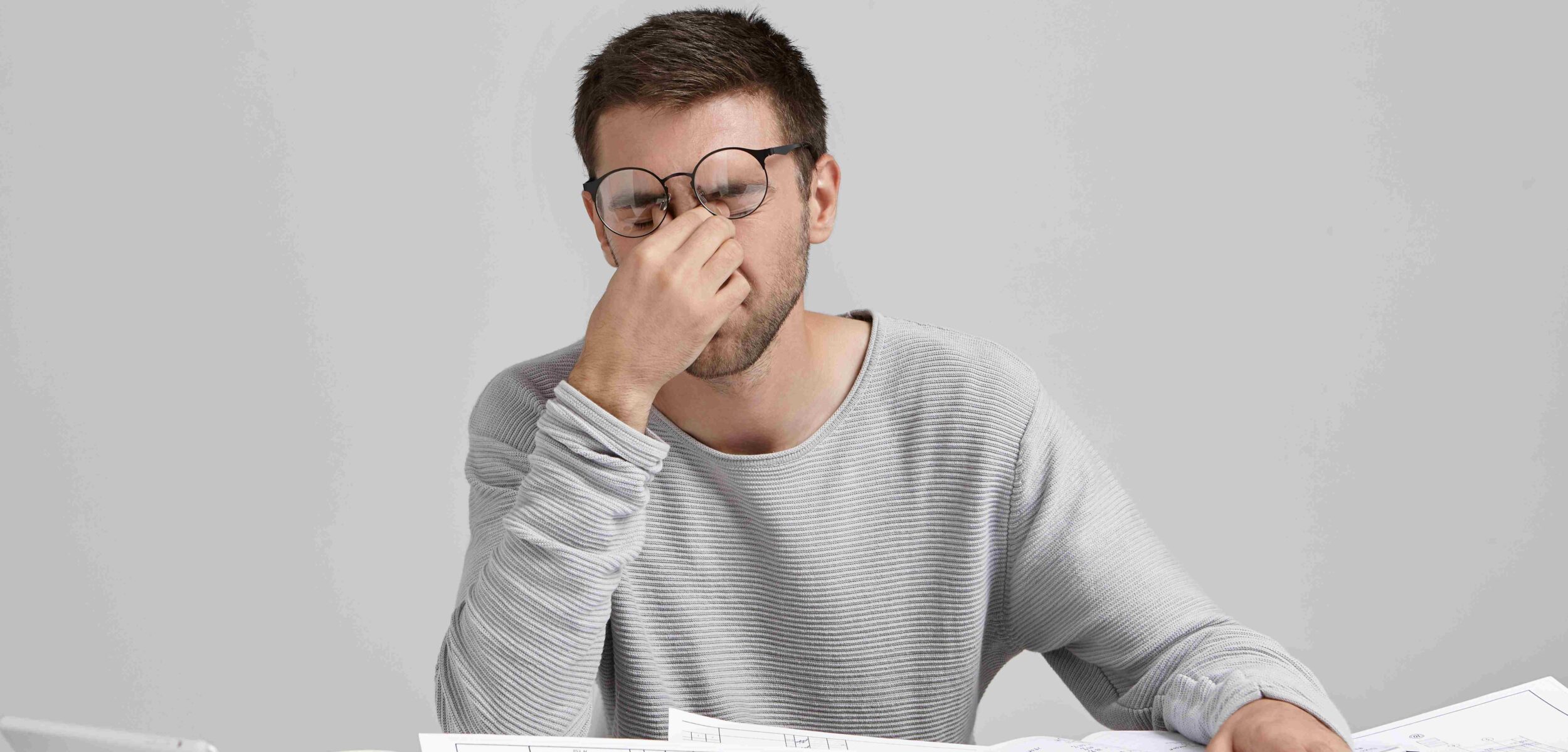 stess overwork deadline tired unshaven young architect freelancer massaging nose bridge 11zon