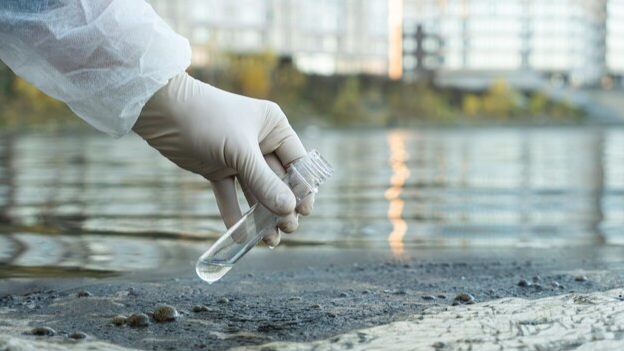 female ecologist protective glove holding test tube with water from city river 431724 13232