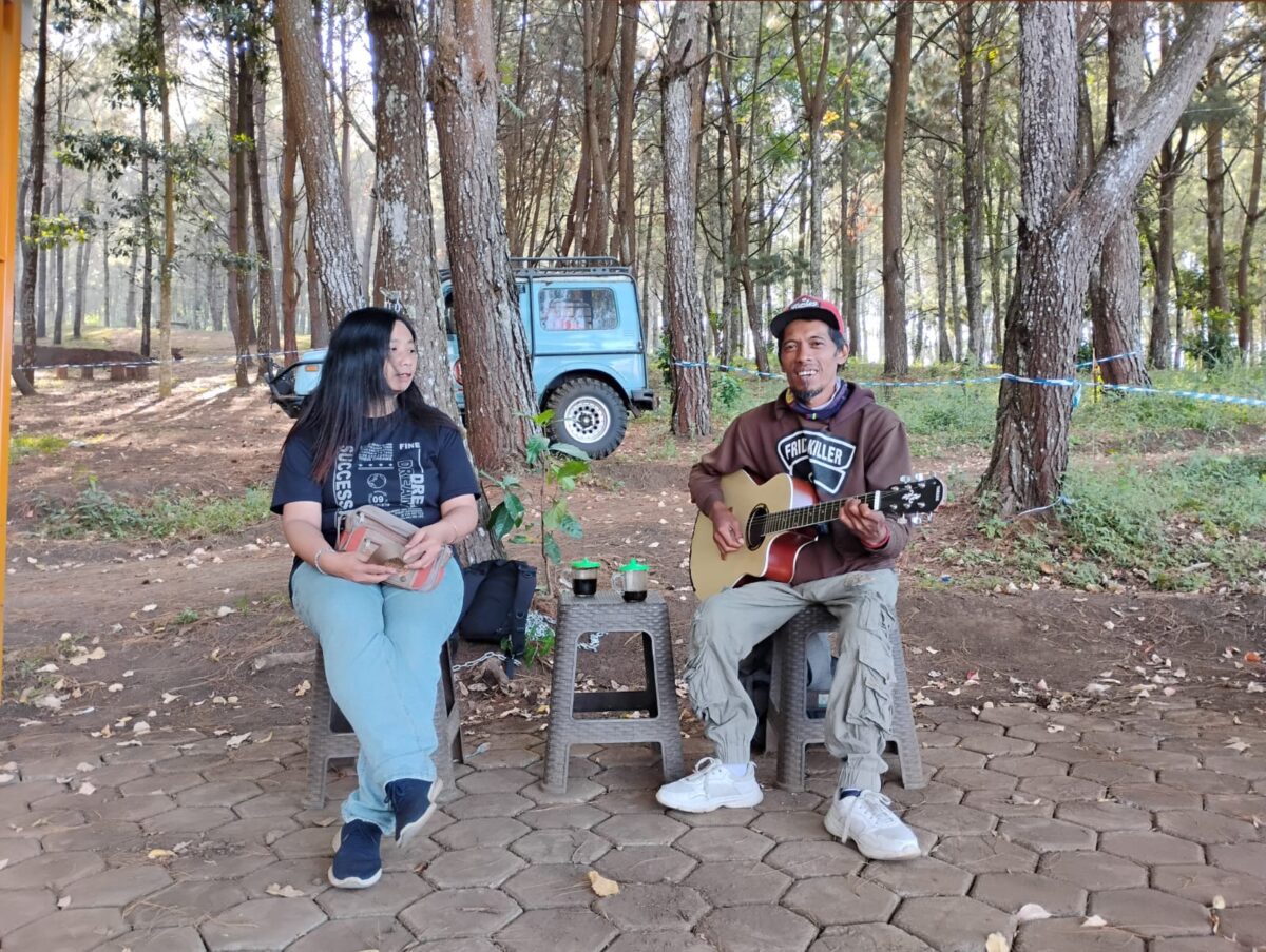 Pengamen penyandang disabilitas, Eko Pramono saat tengah mengamen di Payung Pinus, Jalibar bersama salah seorang wisatawan yang request lagu. (Yan / Kabarterdepan.com)