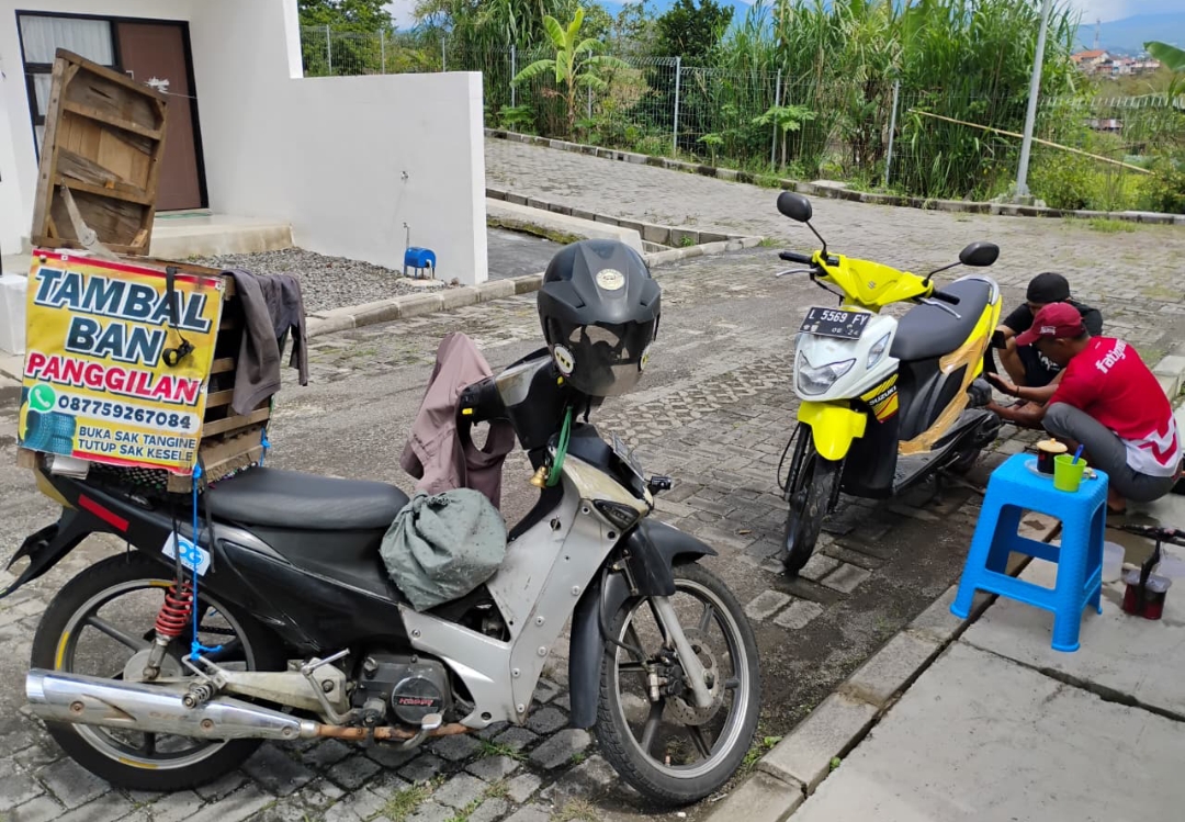Sugianto, tukang tambal ban online di Kota Batu saat melayani pelanggan dengan menambal ban sepeda motor yang bocor. (Yan/kabarterdepan.com) 