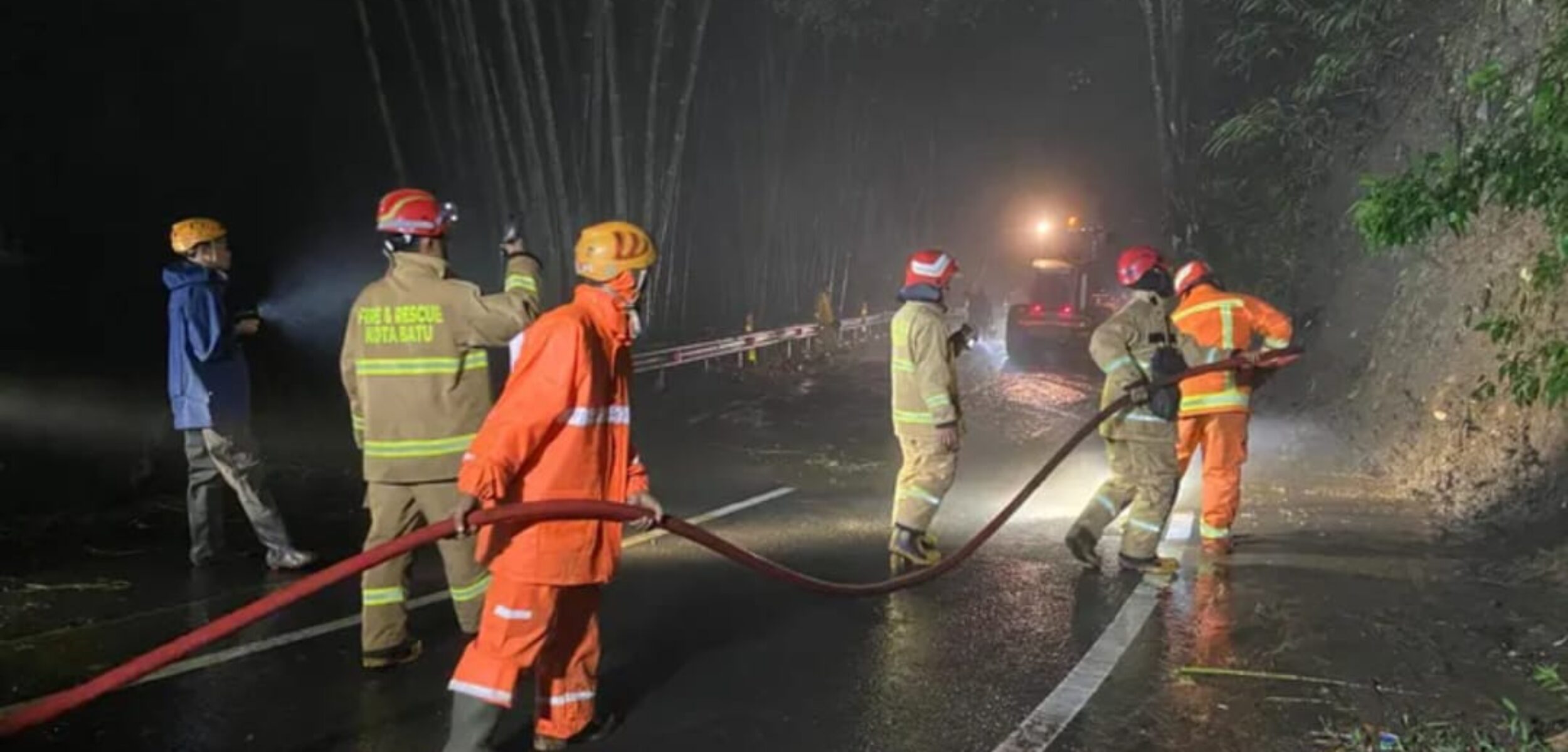 Tim BPBD Kota Batu membersihkan sisa material longsor di jalur Payung Kota Batu. Sabtu (17/1/2026) malam. (Doi/kabarterdepan.com) 